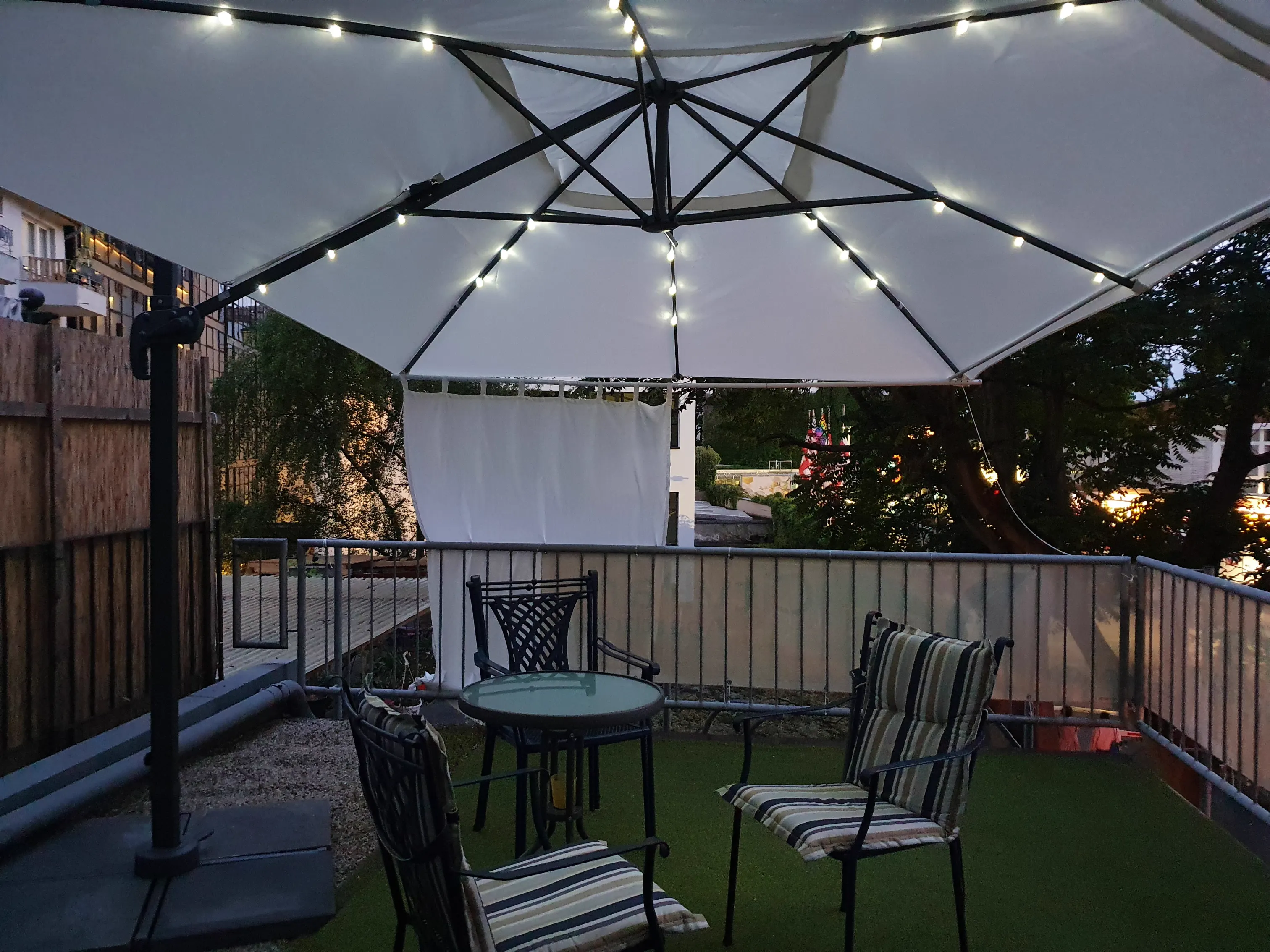 Beleuchtete Terrasse mit Tisch und Stühlen am Abend